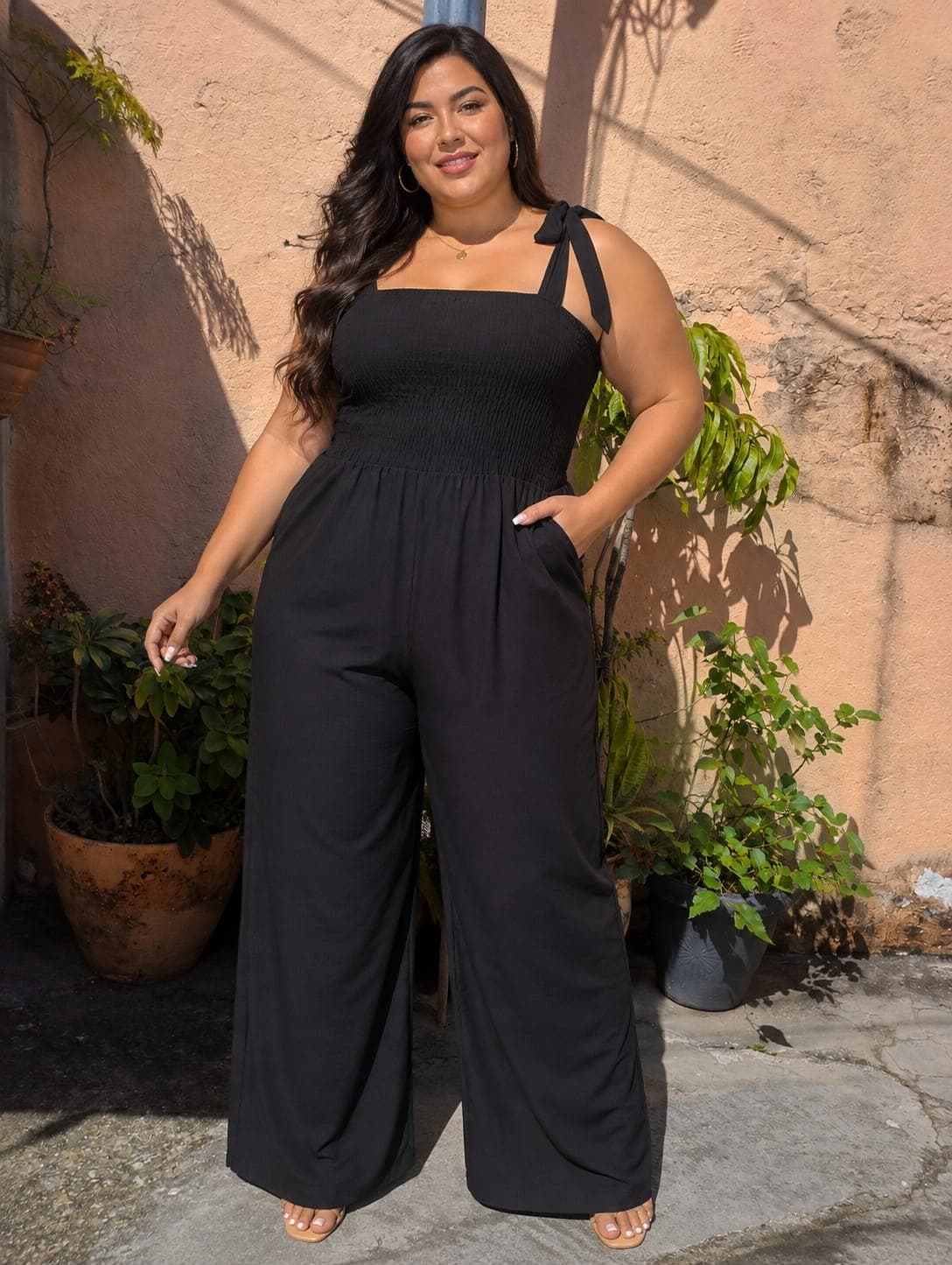 Modelo plus size com macacão preto de alças com laço